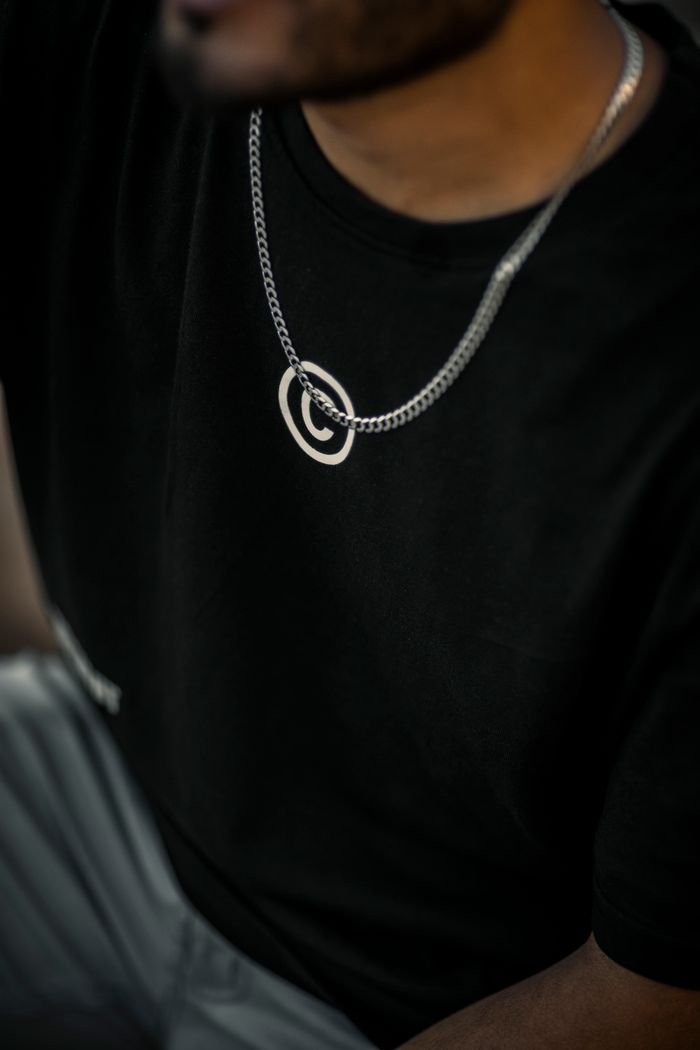 Close-up portrait of a man wearing a black t-shirt and silver chain.