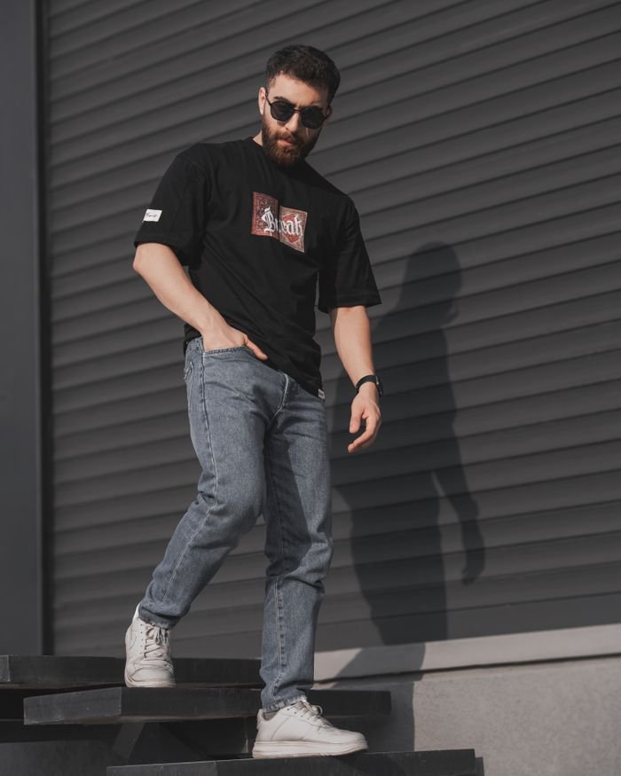 Young man in sunglasses and casual attire poses in urban setting. Perfect for street style and fashion photography.